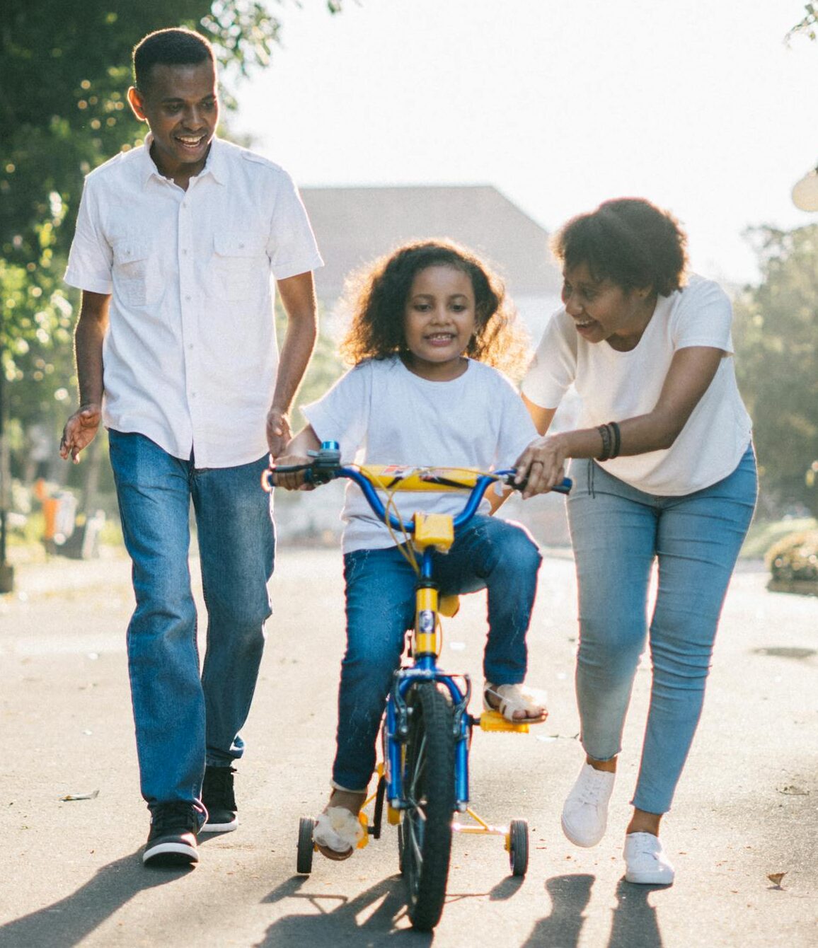 Man Standing Beside His Wife Teaching Their Child How to Ride Bicycle